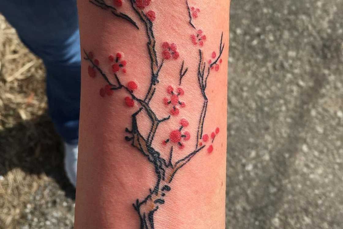 A man with a cherry blossom branch tattoo on the fore arm