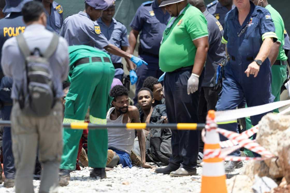 Illegal miners rescued from an abandoned gold mine sit on the floor