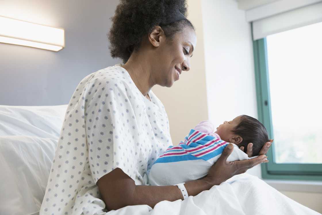 A young mother holding her newborn lovingly. A young mother holding her newborn lovingly.