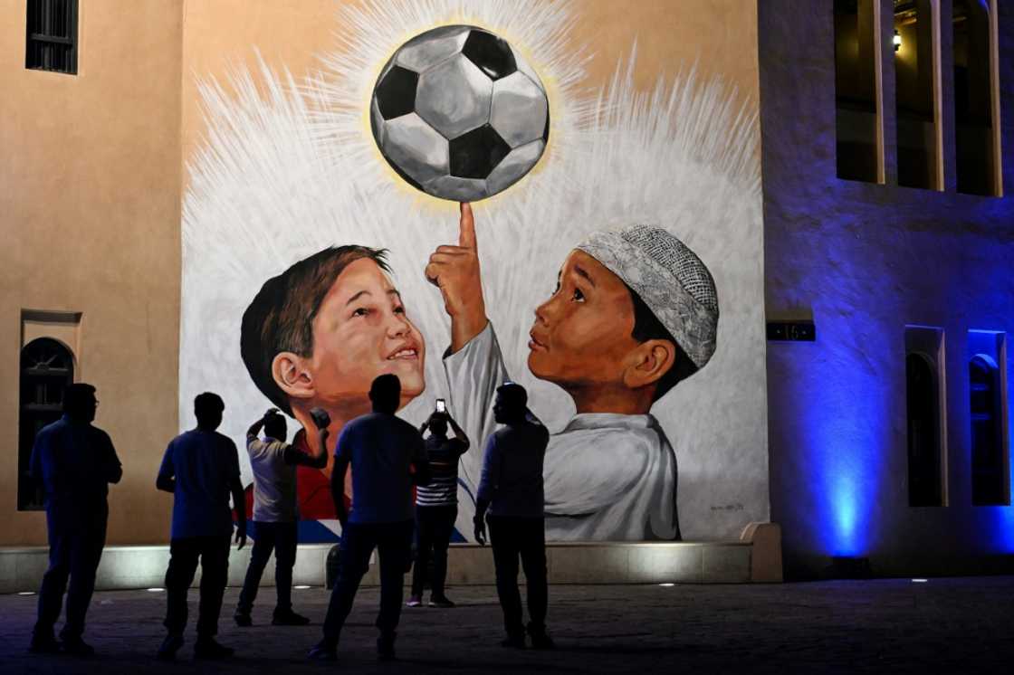 People look at a mural in Doha on November 4, 2022, ahead of the Qatar 2022 FIFA World Cup football tournament. People look at a mural in Doha on November 4, 2022, ahead of the Qatar 2022 FIFA World Cup football tournament.