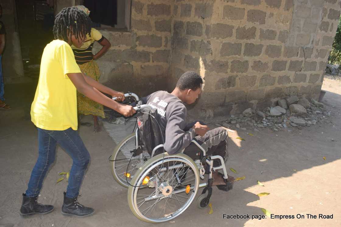 Photo of Empress Esi helping a man living with a disability. Photo of Empress Esi helping a man living with a disability.