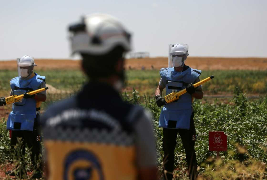 Members of the White Helmets get ready to search for and neutralise unexploded weapons in a field on the outskirts of al-Jinah village Members of the White Helmets get ready to search for and neutralise unexploded weapons in a field on the outskirts of al-Jinah village