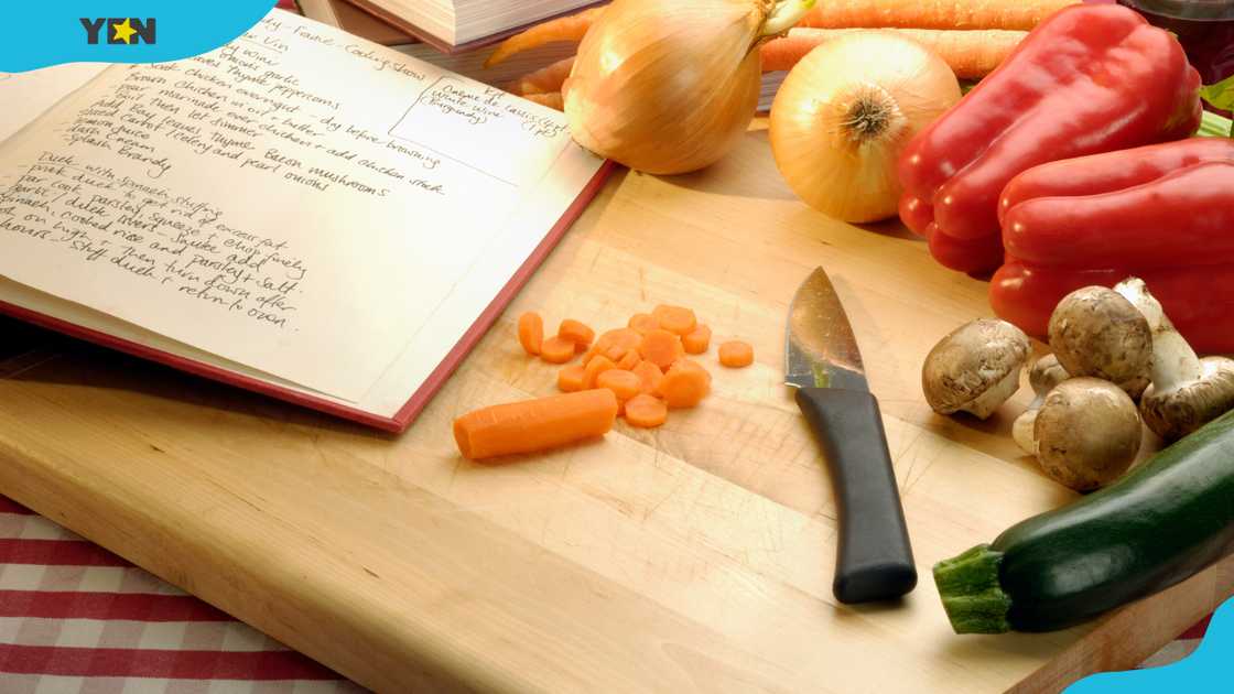 A cookbook and vegetables on a cutting board. A cookbook and vegetables on a cutting board.