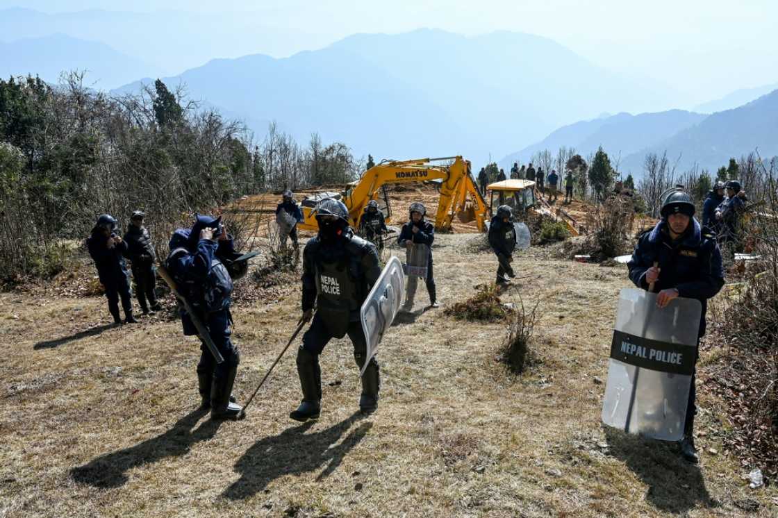 Police stand guard as workers use excavators at the construction site of a cable transportation system leading to the Pathibhara Devi temple Police stand guard as workers use excavators at the construction site of a cable transportation system leading to the Pathibhara Devi temple