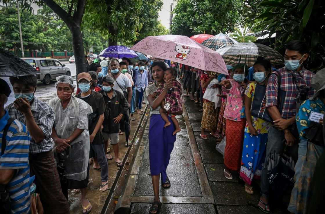 People line up for a free meal along a street in Yangon People line up for a free meal along a street in Yangon