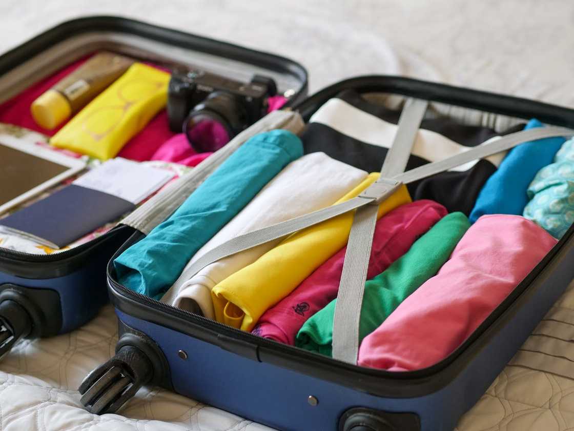 A neatly packed open suitcase sits on a bed with clothes, toiletries, and a camera organised inside. A neatly packed open suitcase sits on a bed with clothes, toiletries, and a camera organised inside.