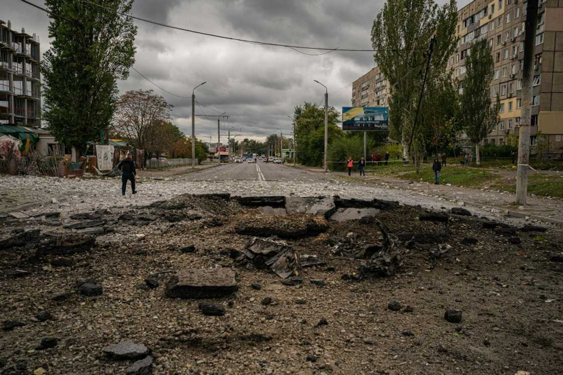 A policeman walks next to a crater following a missile strike in Dnipro A policeman walks next to a crater following a missile strike in Dnipro