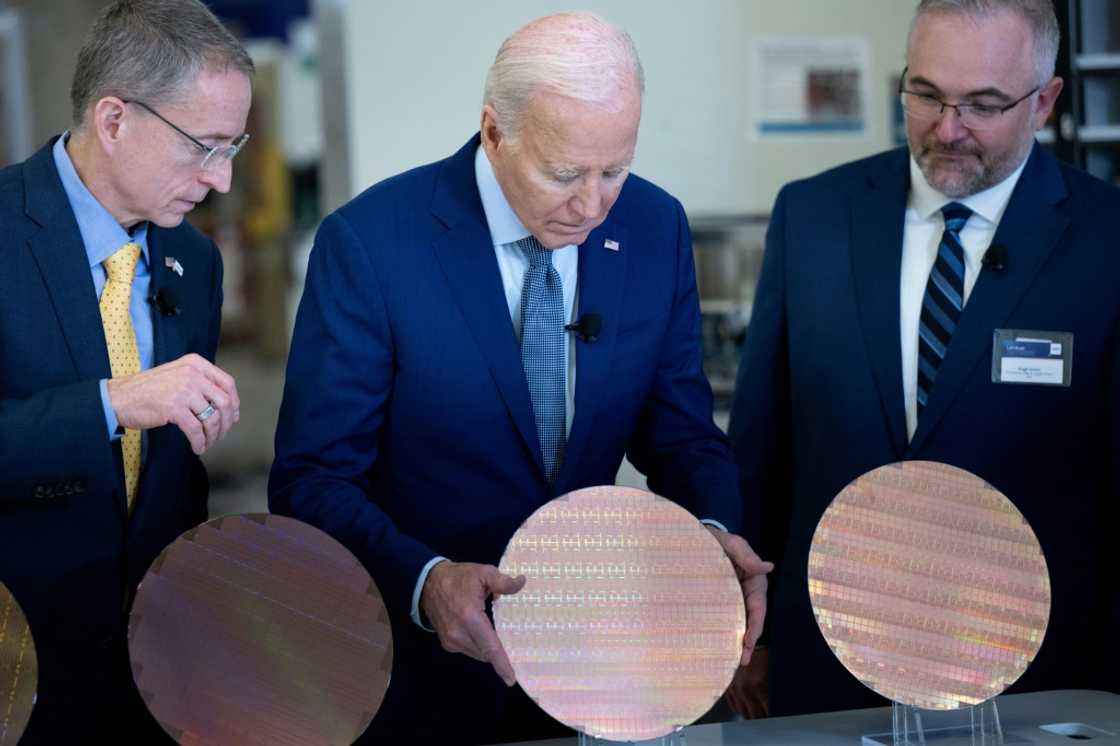 Intel CEO Pat Gelsinger (L) and Intel Factory Manager Hugh Green (R) watch as US President Joe Biden (C) looks at a semiconductor wafer during a tour at Intel Ocotillo Campus in Chandler, Arizona