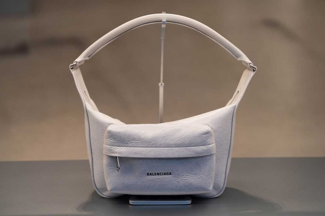 White Balenciaga Raver handbag with white handle on a table. White Balenciaga Raver handbag with white handle on a table.