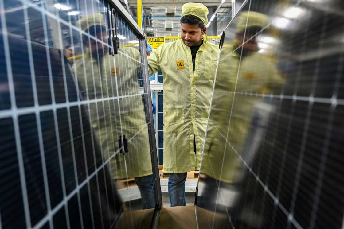 An employee inspects solar panels at an Adani Group factory in Mundra An employee inspects solar panels at an Adani Group factory in Mundra