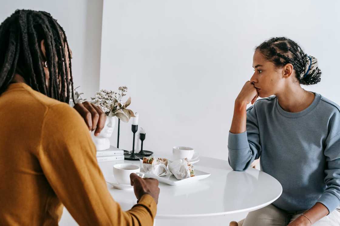 A couple sitting at a table in tense silence during a serious conversation.