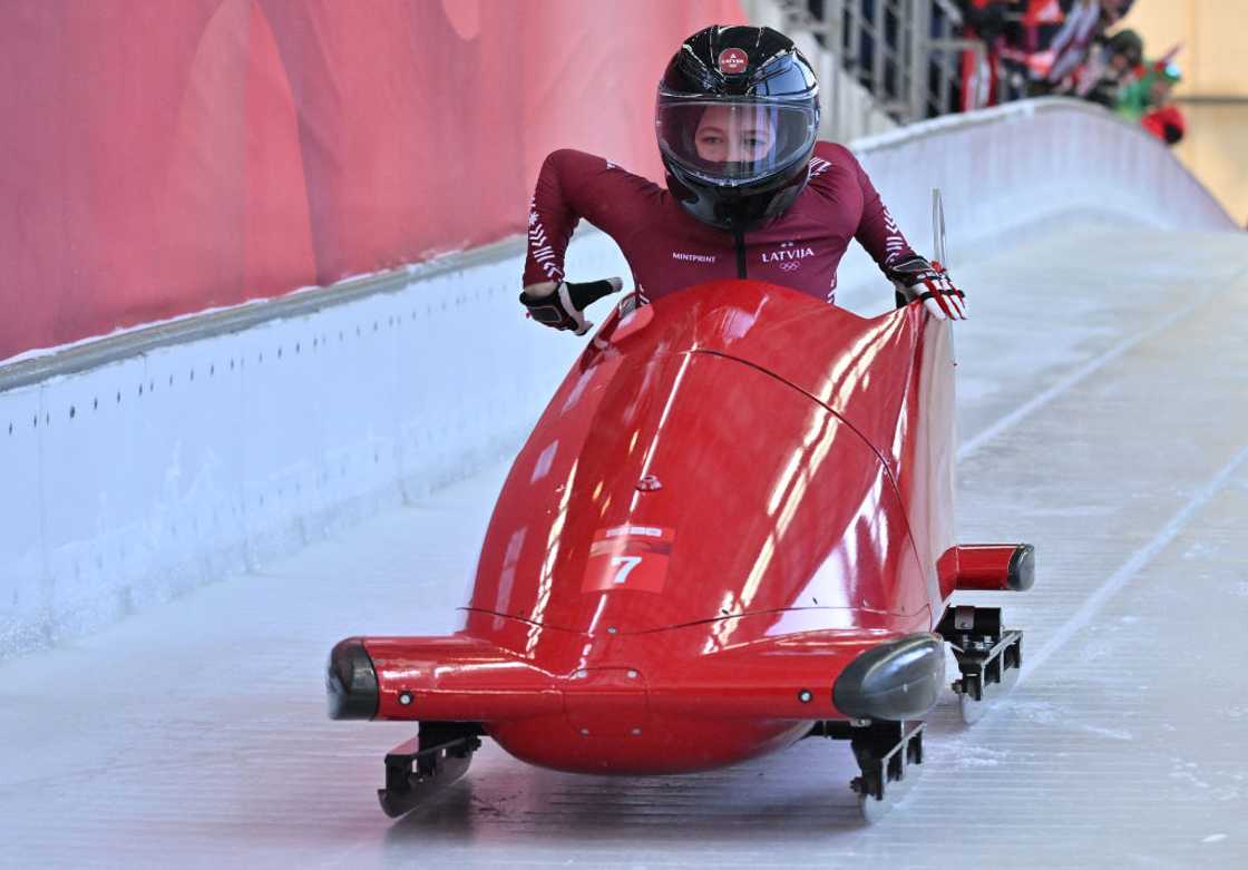 A person joyfully sleds down a track on a red sled. A person joyfully sleds down a track on a red sled.