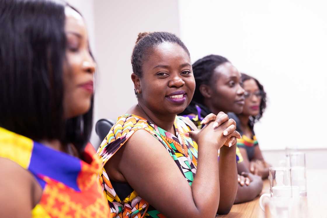 Women smiling during a stokvel meeting.