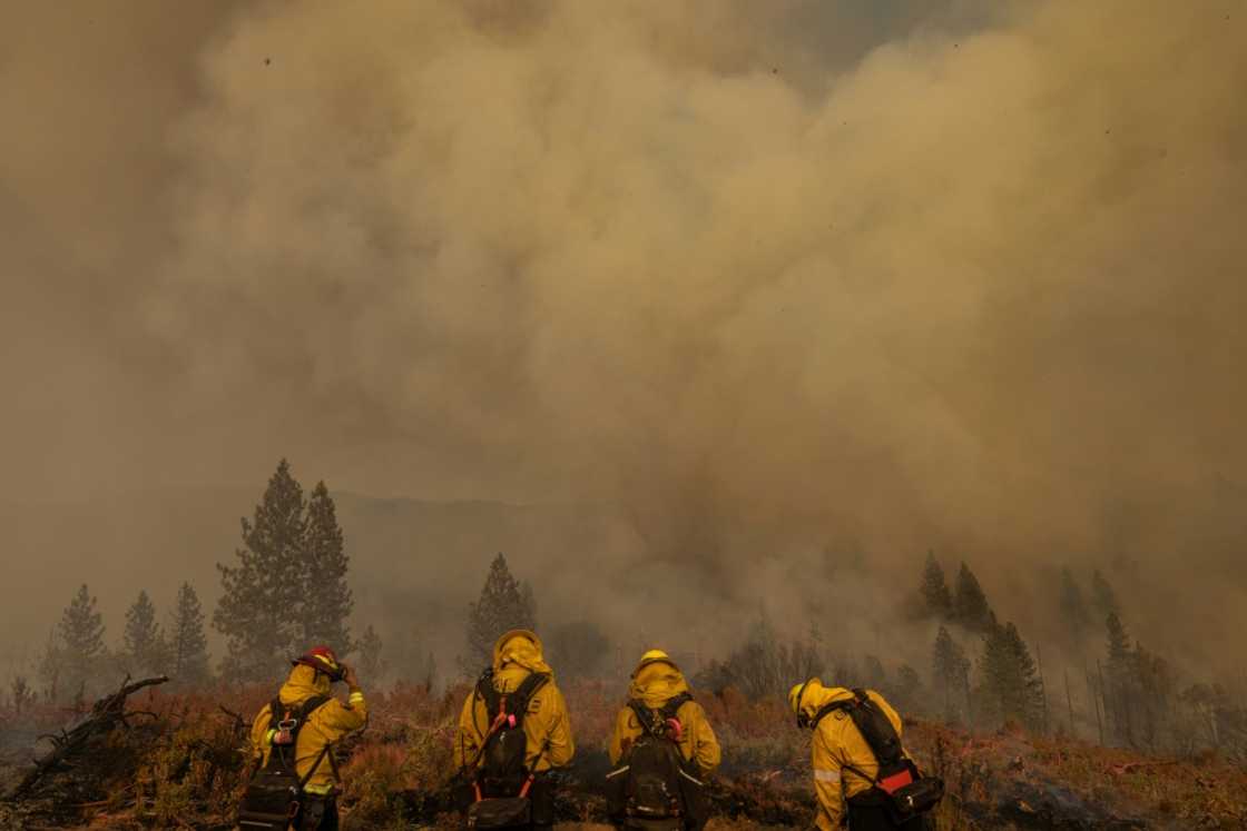 Smoke rises behind firefighters at at the Oak Fire in Mariposa, California