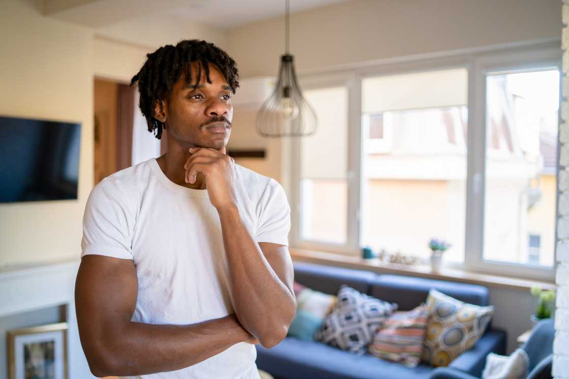 A man looking away from the camera, holding one hand to his neck
