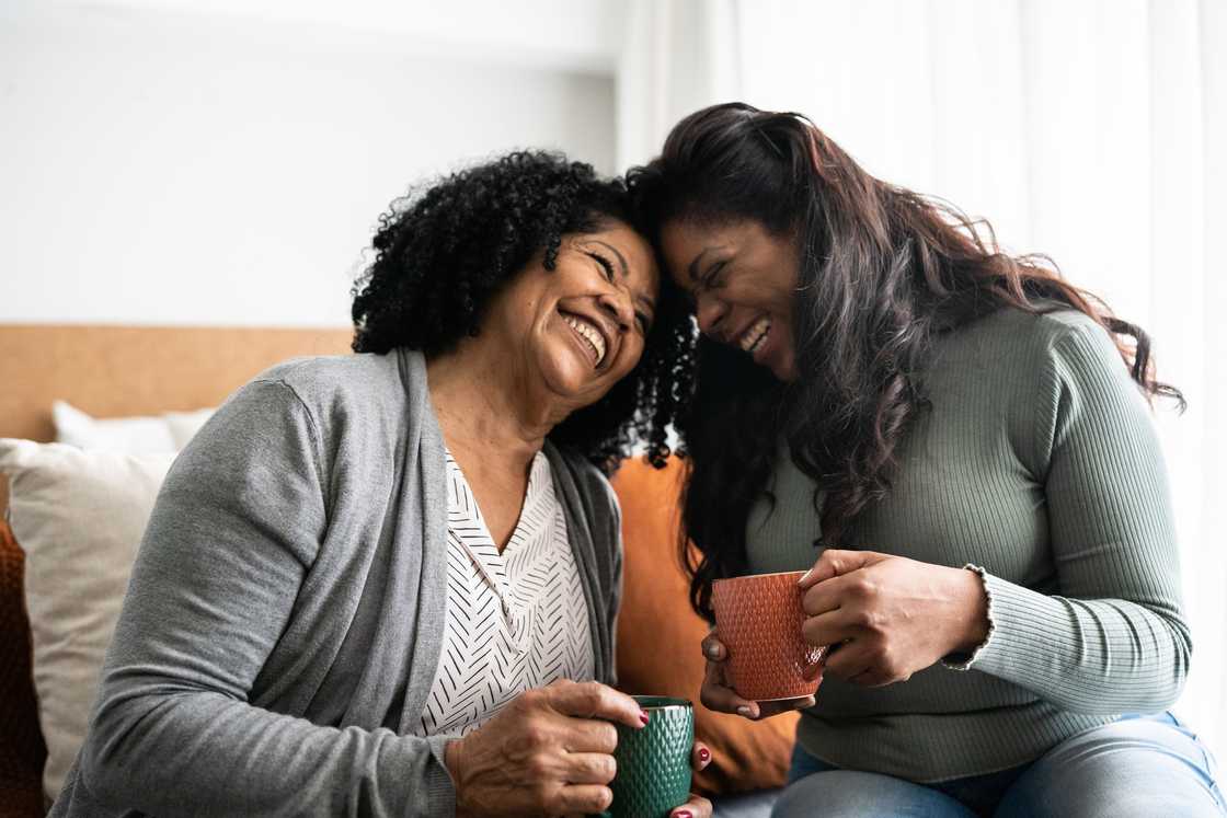 Two women laughing while gossiping Two women laughing while gossiping