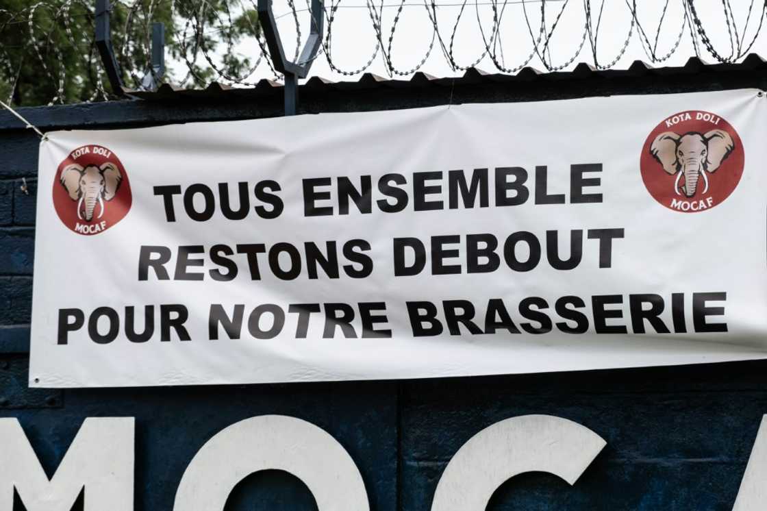 A sign on the brewery fence says 'Let's all stand together for our brewery' A sign on the brewery fence says 'Let's all stand together for our brewery'
