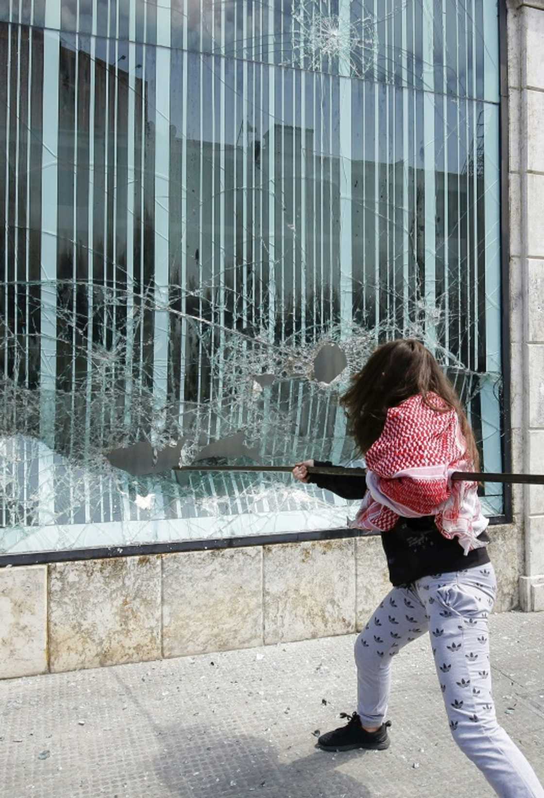 A Lebanese protester smashes the facade of a bank at Al-Nour square in Lebanon's northern port city of Tripoli, on April 28, 2020 A Lebanese protester smashes the facade of a bank at Al-Nour square in Lebanon's northern port city of Tripoli, on April 28, 2020