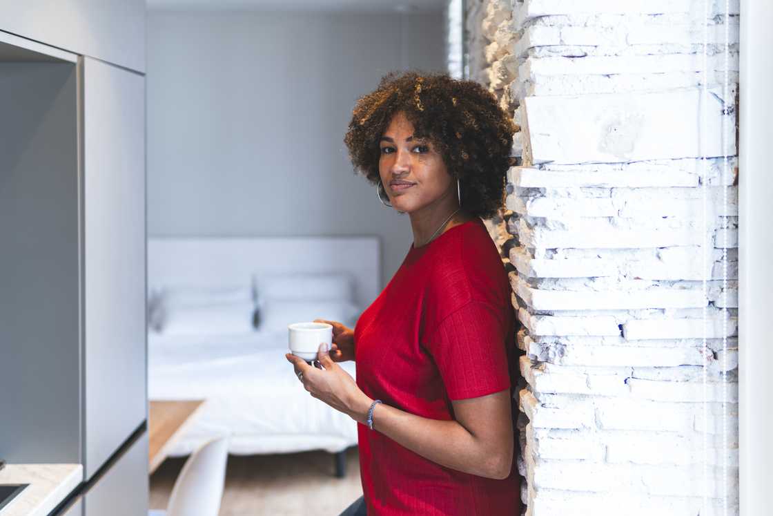 A woman poses in with a coffee cup. A woman poses in with a coffee cup.