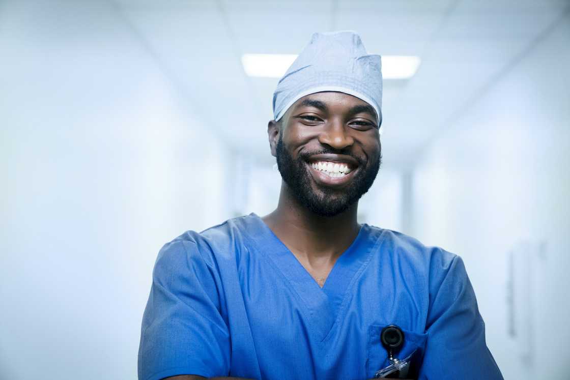 A Black nurse in blue uniform smiling