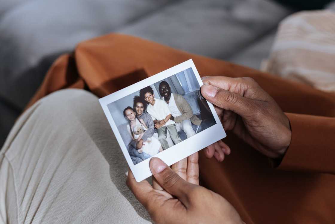 A person holds a small printed family photograph.