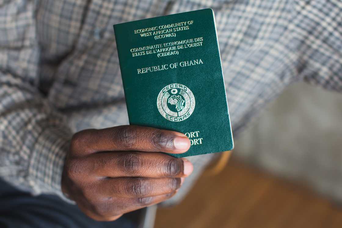 A hand holding a passport from Ghana A hand holding a passport from Ghana
