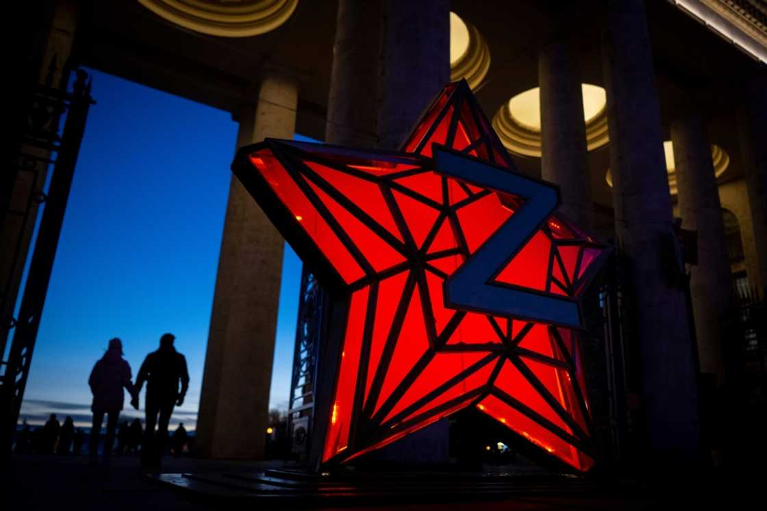 Pedestrians walk past a New Year decoration stylised as the 'Kremlin Star,' bearing a Z letter, a tactical insignia of Russian troops in Ukraine