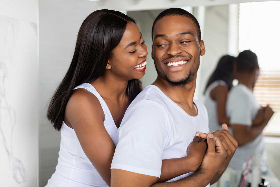 A happy couple embrace near a mirror in the bathroom A happy couple embrace near a mirror in the bathroom