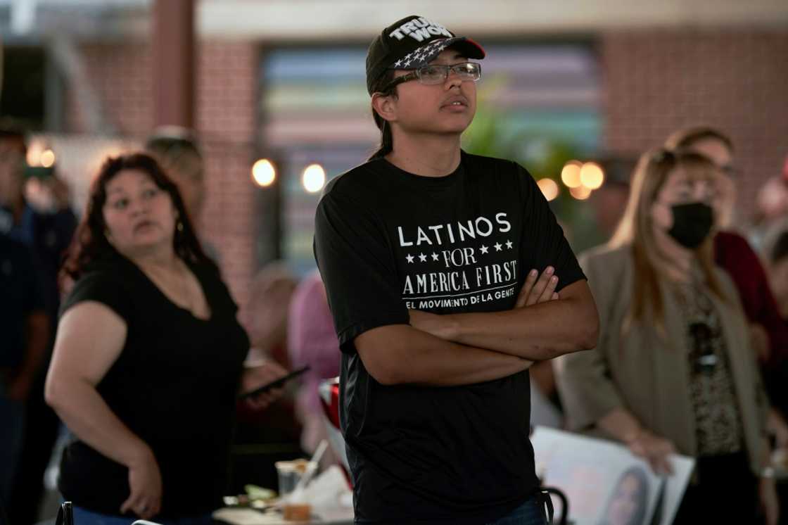 A man wearing a T-shirt that says, "Latinos for América First" attends a rally in McAllen, Texas, on October 10, 2022 A man wearing a T-shirt that says, "Latinos for América First" attends a rally in McAllen, Texas, on October 10, 2022