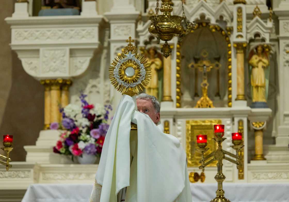 A priest holding up a cross inside a church A priest holding up a cross inside a church