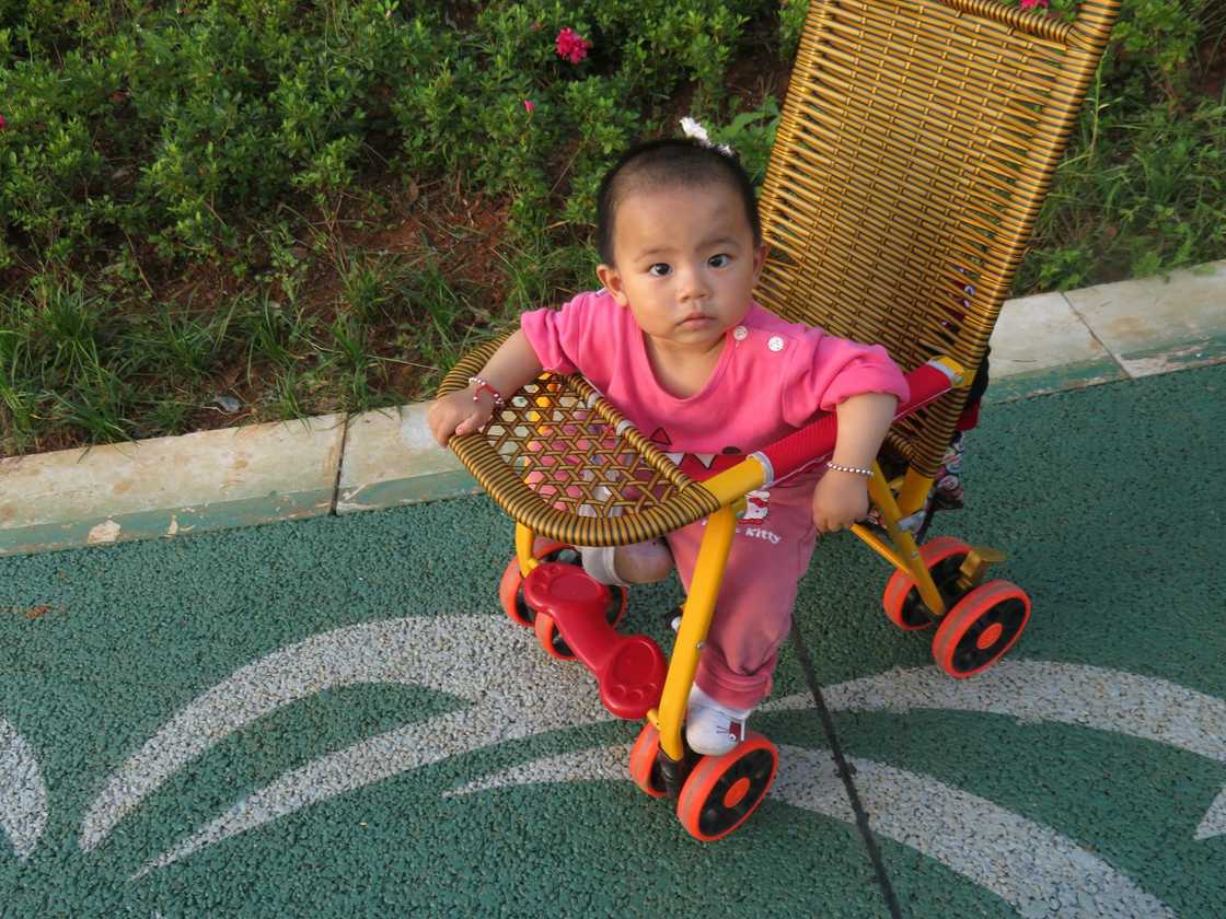 A cute baby girl sitting on a woven stroller A cute baby girl sitting on a woven stroller
