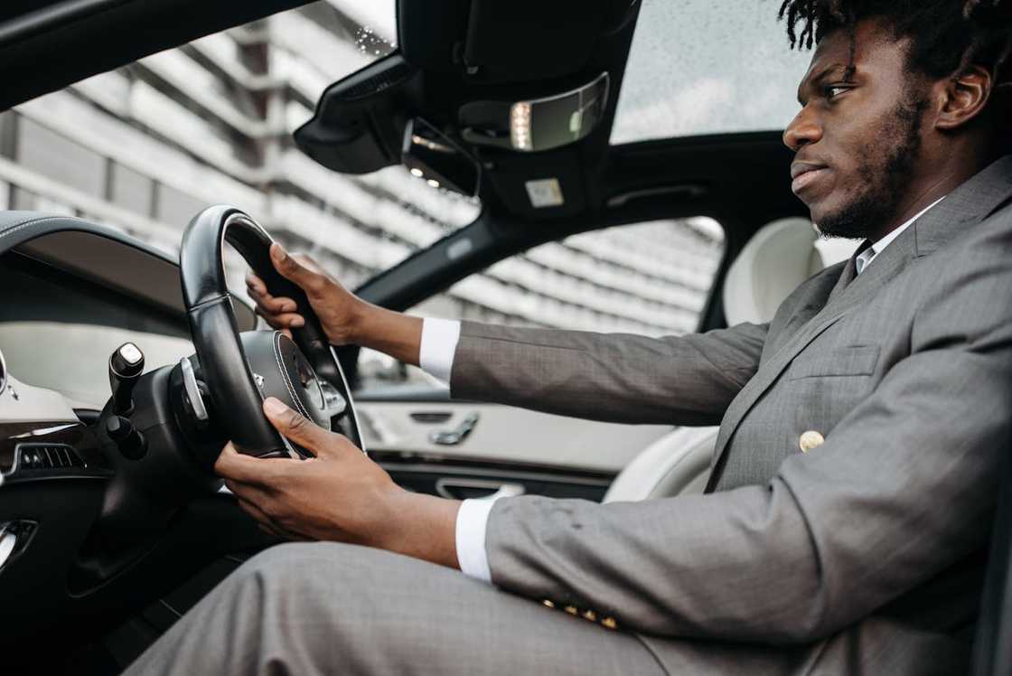 A man in a suit driving a car, focused on the road. A man in a suit driving a car, focused on the road.