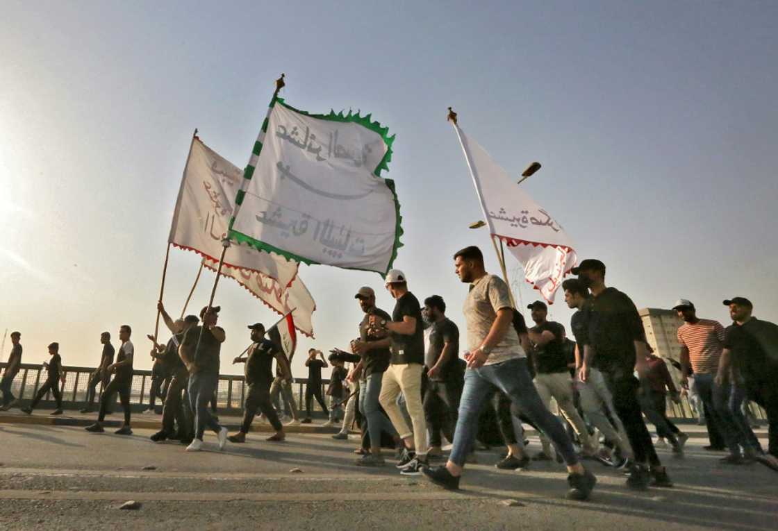 Supporters of Iraqi cleric Moqtada Sadr wave flags during a rally protesting a rival political bloc's nomination for prime minister on Monday