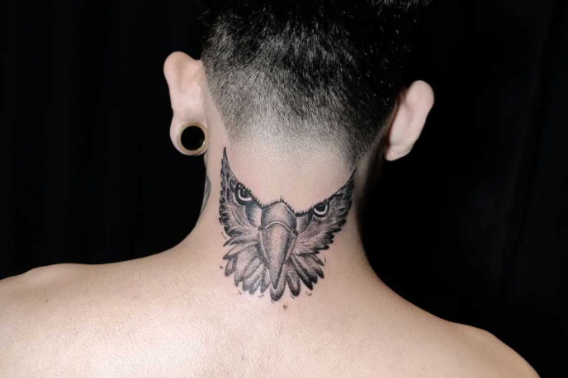 A white man is wearing a half-owl tattoo on the back of his neck A white man is wearing a half-owl tattoo on the back of his neck