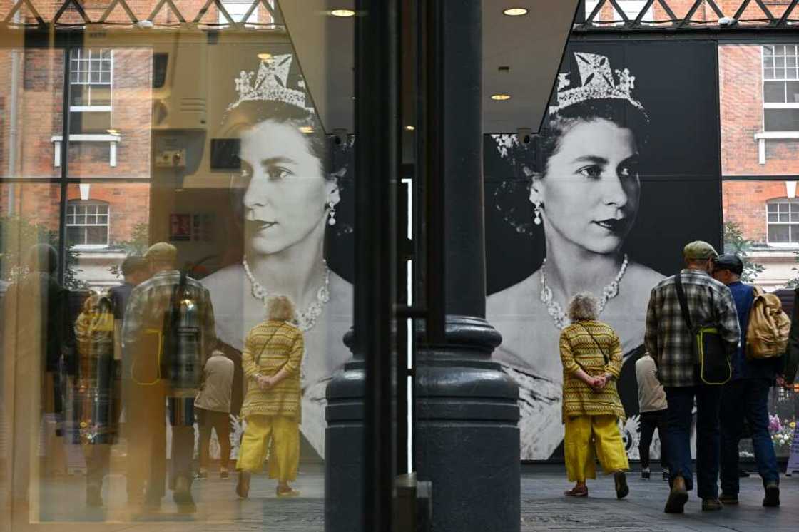 People walk past a giant portrait of Britain's Queen Elizabeth II in Spitafields Market in London, on September 16, 2022 People walk past a giant portrait of Britain's Queen Elizabeth II in Spitafields Market in London, on September 16, 2022