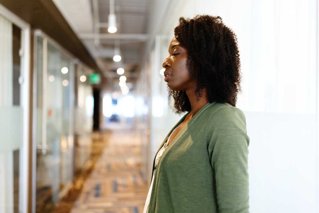 Person in green cardigan stands in hallway. Person in green cardigan stands in hallway.
