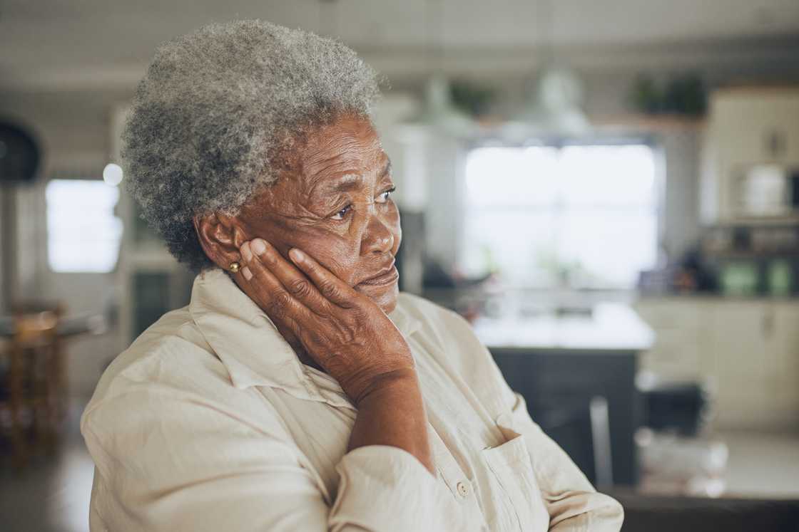 An elderly woman holds herself in a sad manner. An elderly woman holds herself in a sad manner.