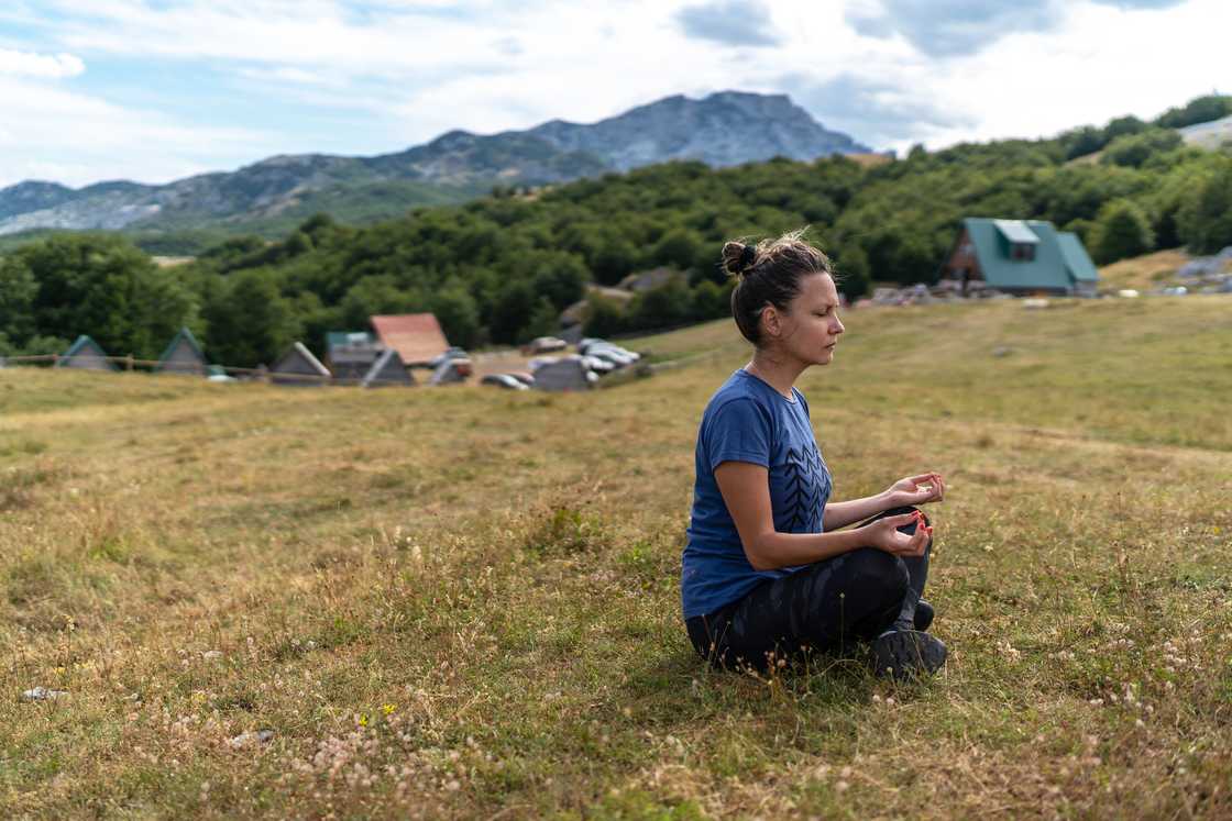 A young woman meditates in the mountains. A young woman meditates in the mountains.