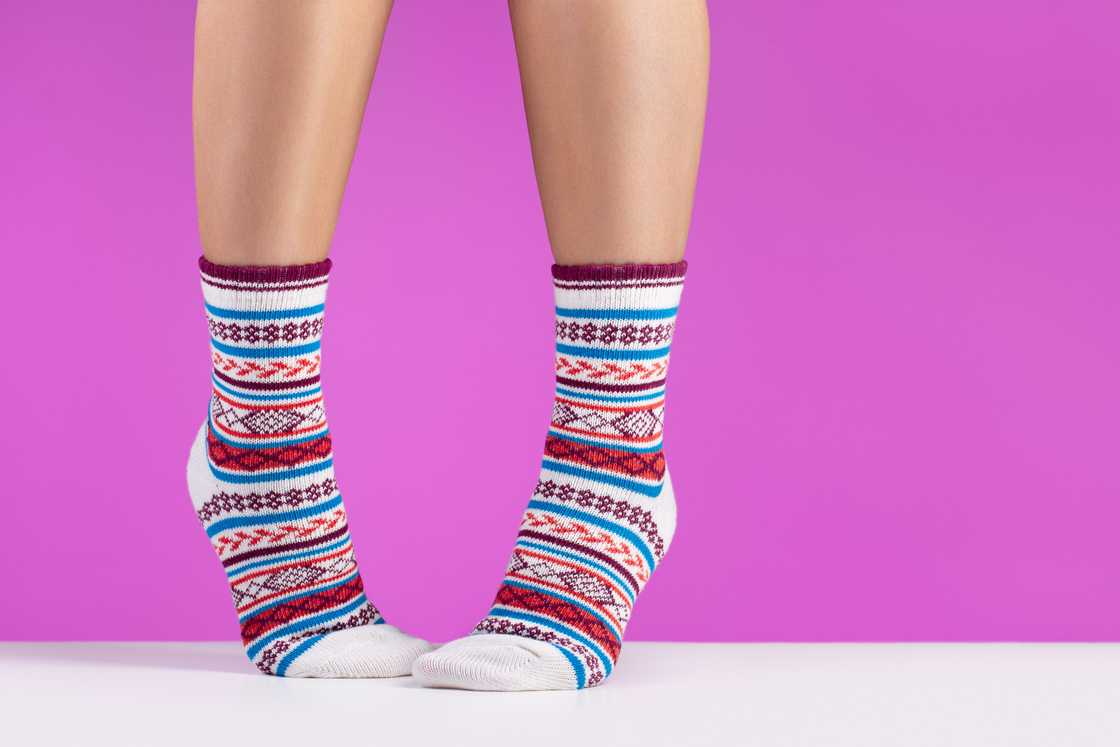 A woman raises her feet and shows off her multi-coloured pair of quarter-length socks