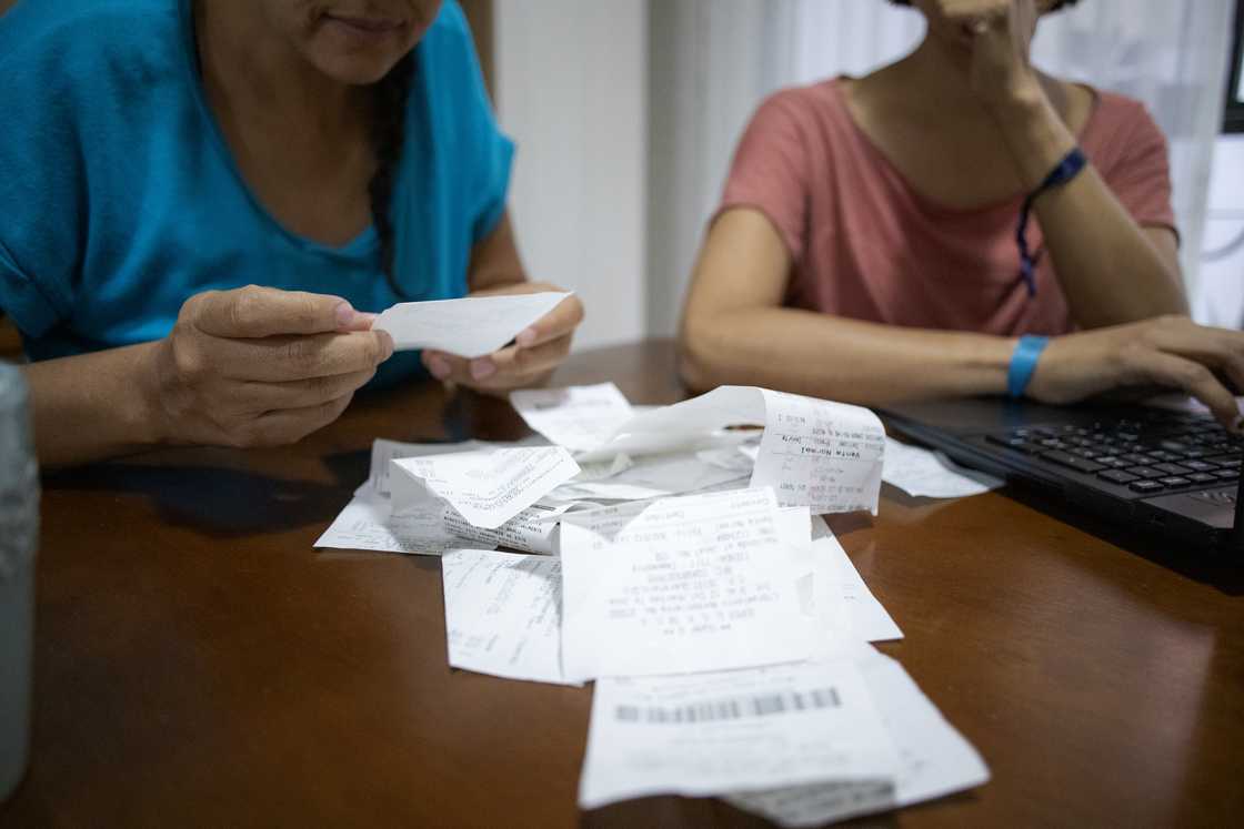 Women sort through receipts during a meeting. Women sort through receipts during a meeting.