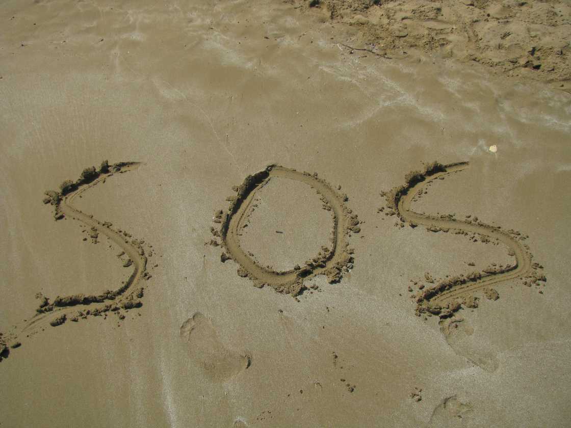 The word 'sos' is written on the sand on the beach. The word 'sos' is written on the sand on the beach.