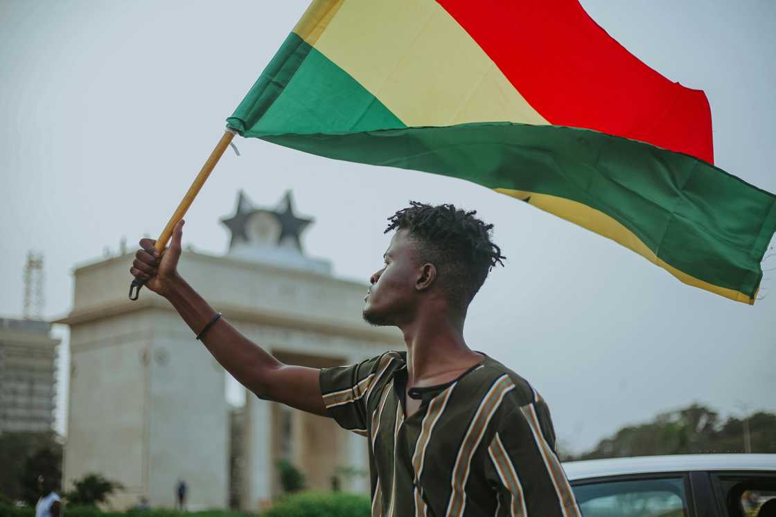 A young man holding the Ghanaian flag at the Black Star Gate A young man holding the Ghanaian flag at the Black Star Gate