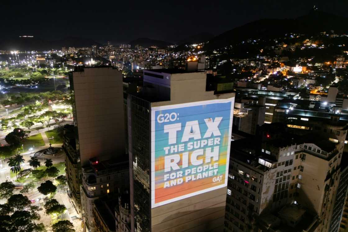 A group of environmental activists projects on a building slide with a silhouette depicting US president-elect Donald Trump that reads, "Tax the super rich for the people and planet" on November 18, 2024, in Rio de Janeiro, Brazil, during the G20 Summit. ONG environment demonstrates projecting slides to demand governments to take actions and tax the superriches for the benefit of the planet.