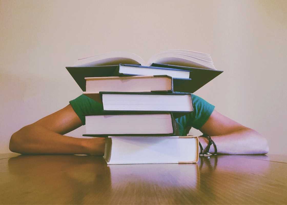 A student lying a desk with a heap of book A student lying a desk with a heap of book