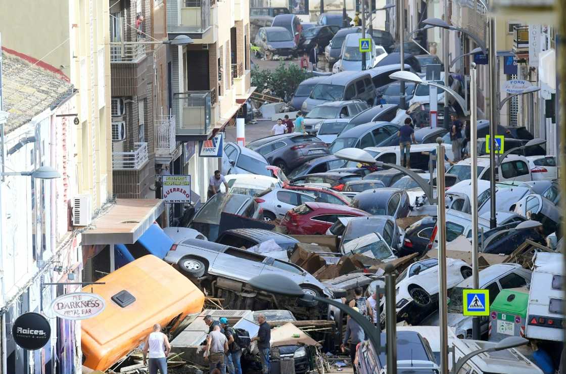 Pedestrians stand next to piled-up cars following deadly floods in Sedavi in the eastern Valencia region of Spain Pedestrians stand next to piled-up cars following deadly floods in Sedavi in the eastern Valencia region of Spain
