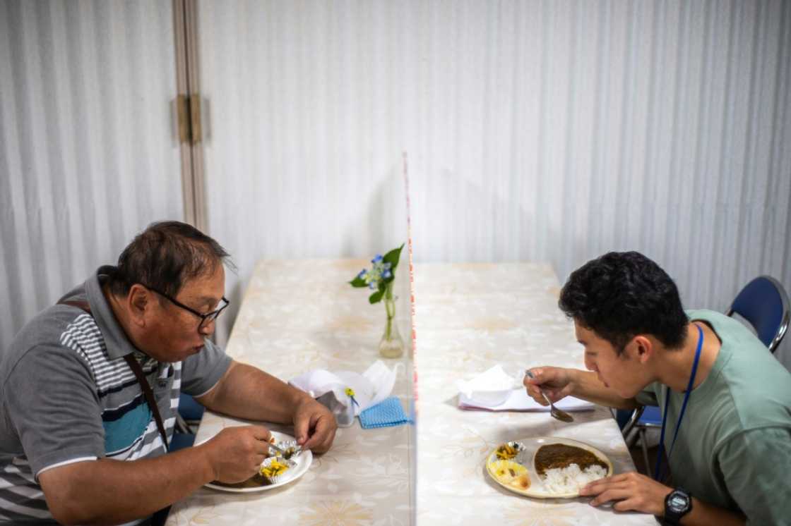 Koichi Miyatsu (R) and his adoptive father Yoshimitsu eat curry together after their monthly charity event at a church in Kumamoto Koichi Miyatsu (R) and his adoptive father Yoshimitsu eat curry together after their monthly charity event at a church in Kumamoto
