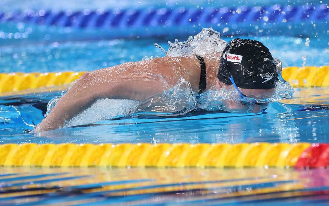 A swimmer wearing a headband in a pool, gracefully gliding through the water. A swimmer wearing a headband in a pool, gracefully gliding through the water.