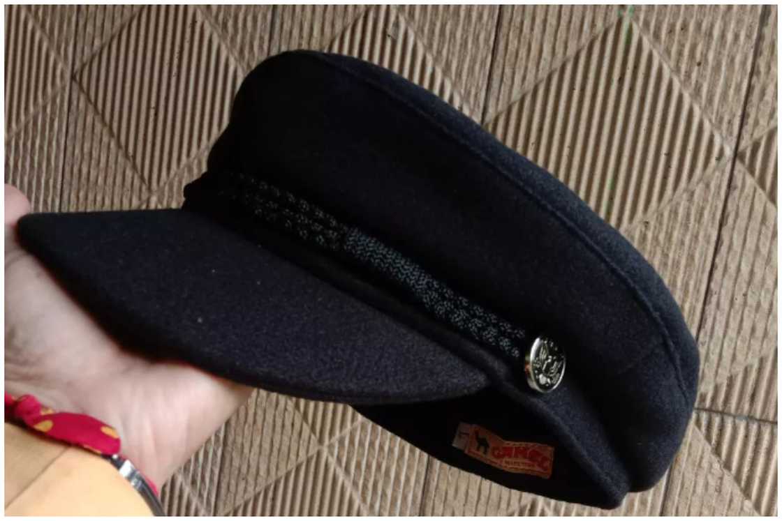 A woman is holding a black men's sailor hat