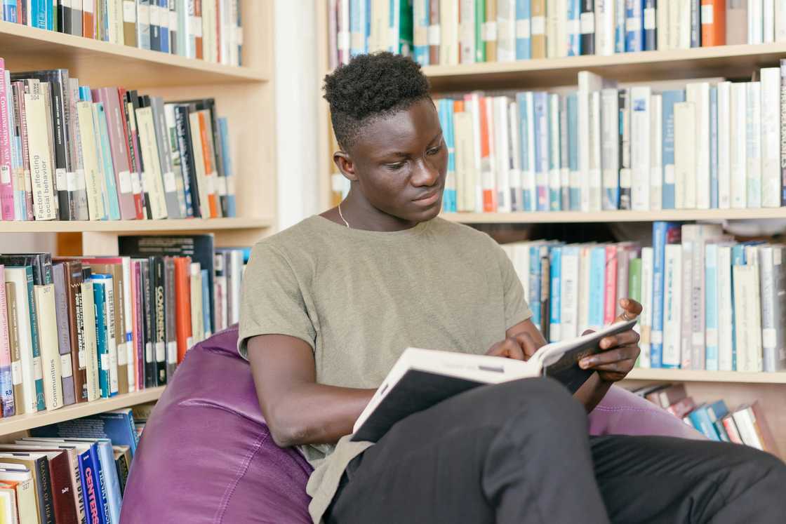 A young man is reading a book in a library