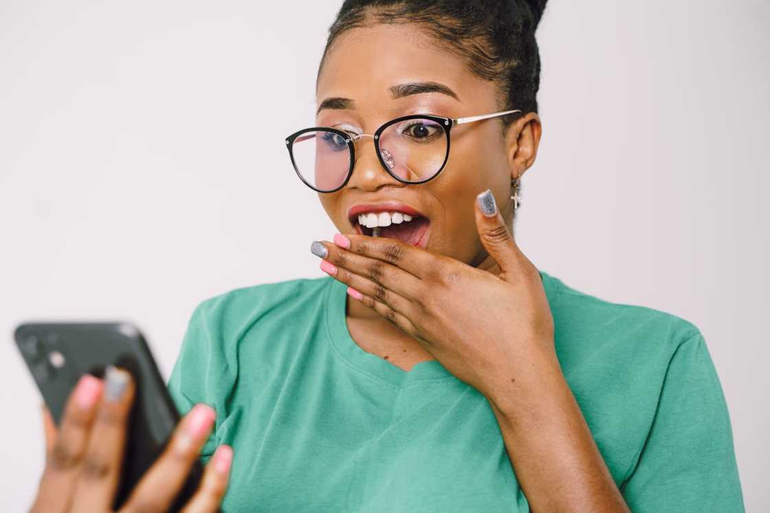 A woman reacts with surprise while looking at her phone. A woman reacts with surprise while looking at her phone.